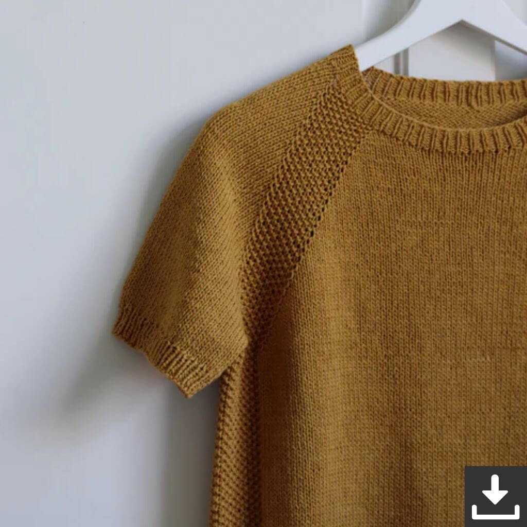 Ein senffarbener Pullover mit kurzen Ärmeln, der auf einem Kleiderbügel hängt.