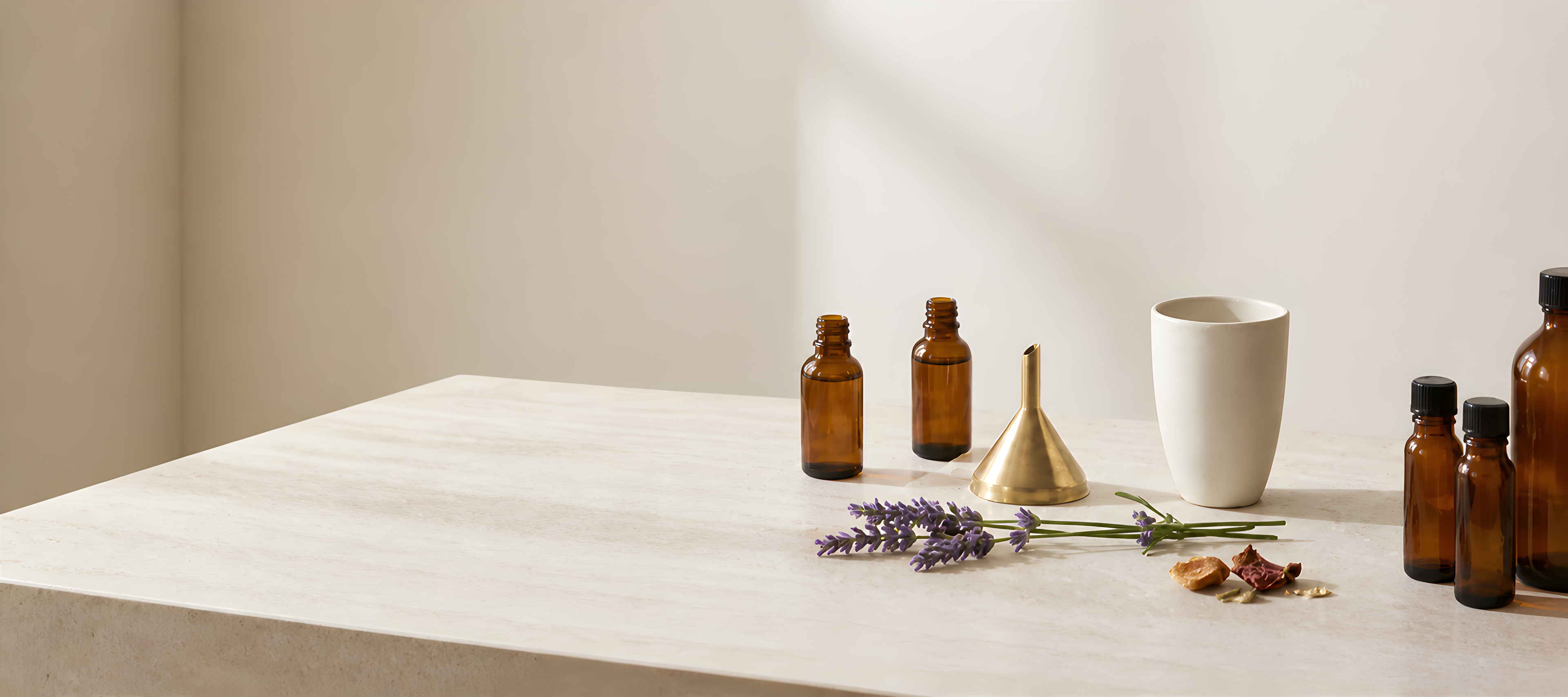 Bottles, a funnel, and lavender on a light wooden table.