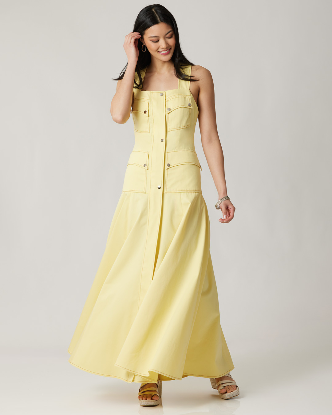Woman in a yellow maxi dress, smiling and posing.