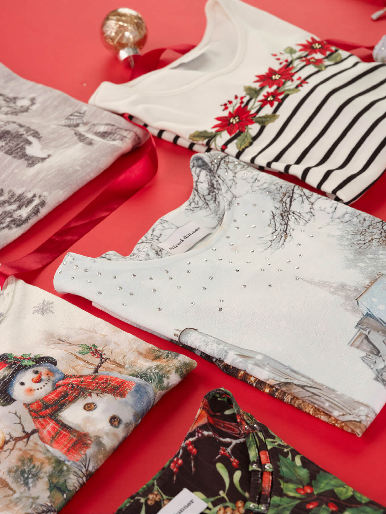 Assorted holiday-themed shirts arranged on a red background.