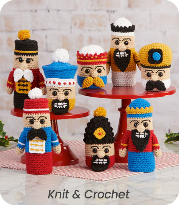 Colorful crocheted nutcracker dolls displayed on a red stand.