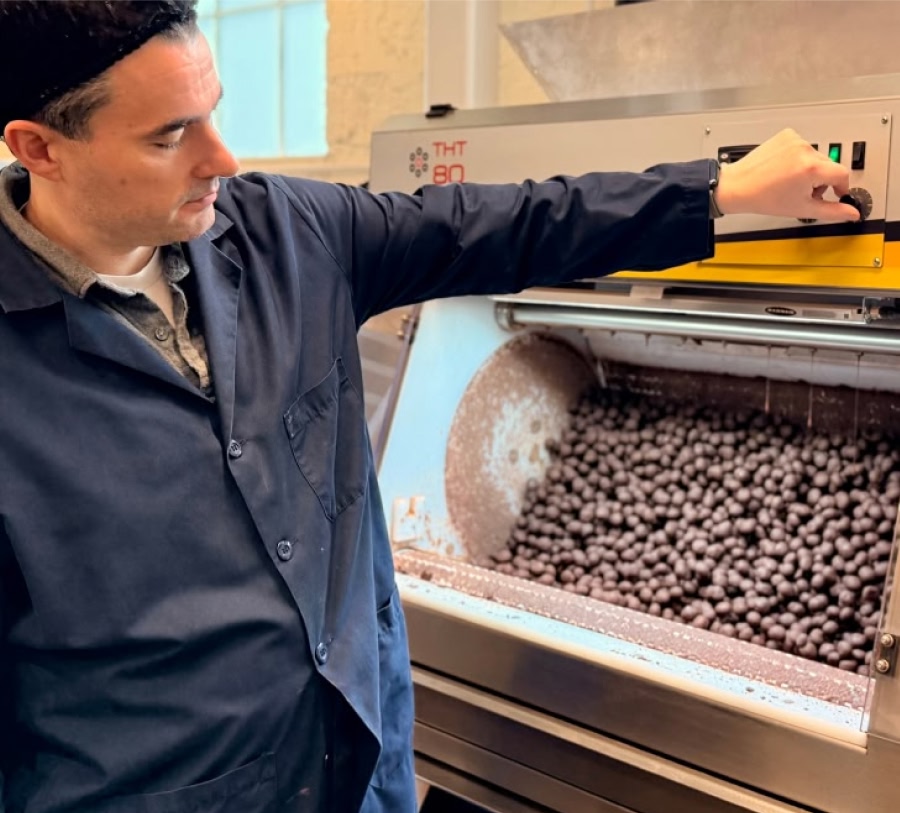 Person operating a machine with chocolate balls inside.