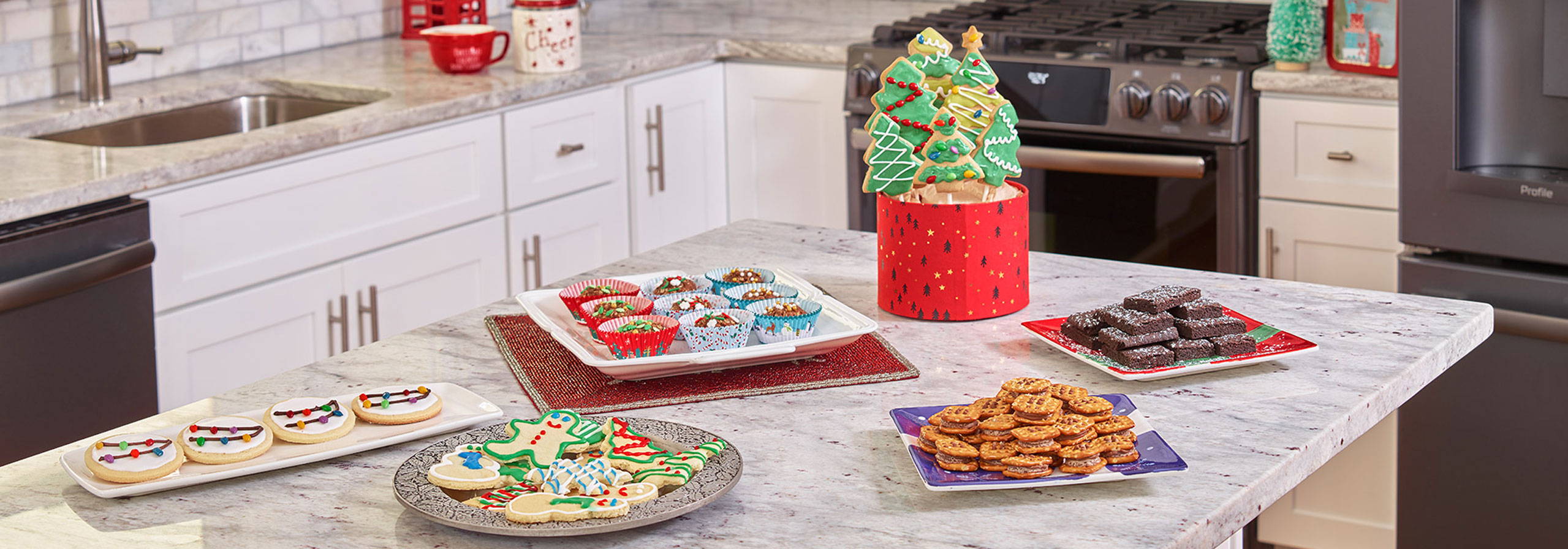 Lots of different holiday cookies on the kitchen island in front of the range and refrigerator.