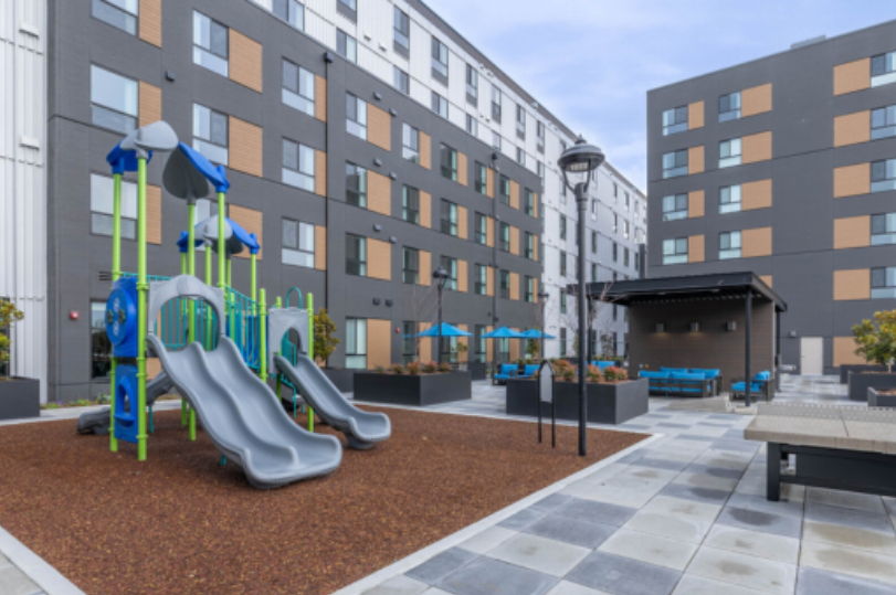 Playground with slides and seating area in a residential complex.
