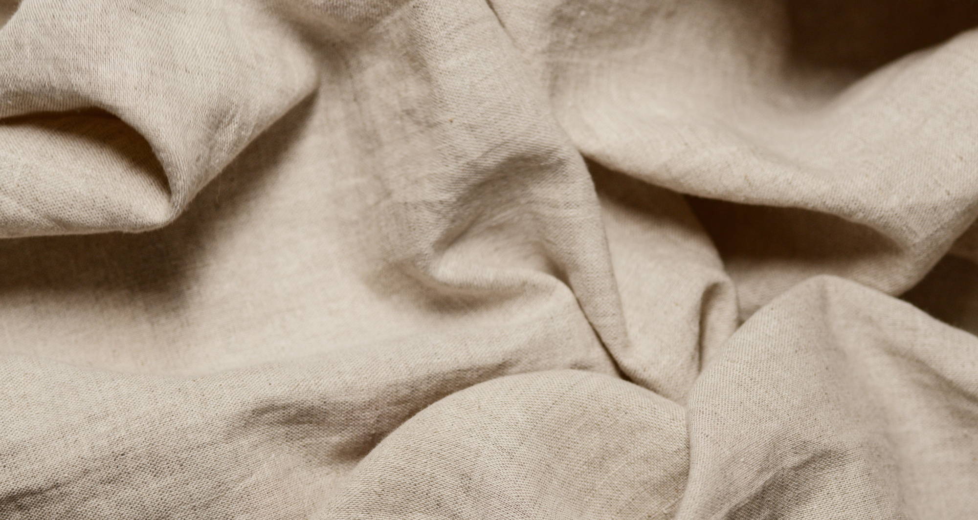 A skein of tan fabric is wrinkled and bunched and close-up enough to see the fabric texture.