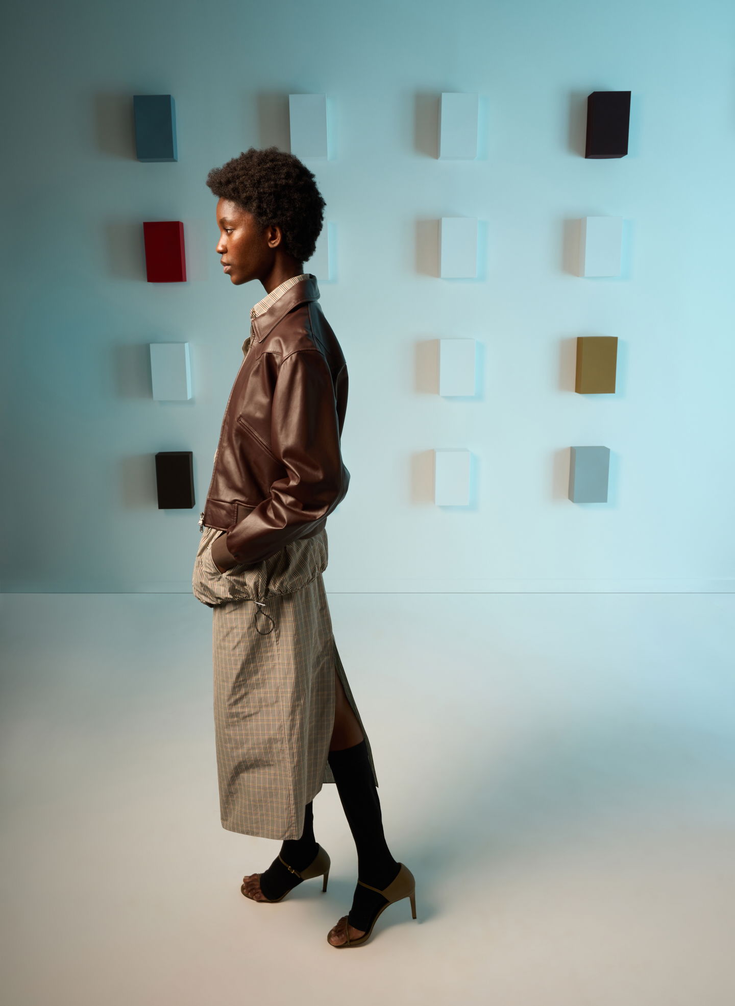 Model in stylish outfit posing against a colorful backdrop.