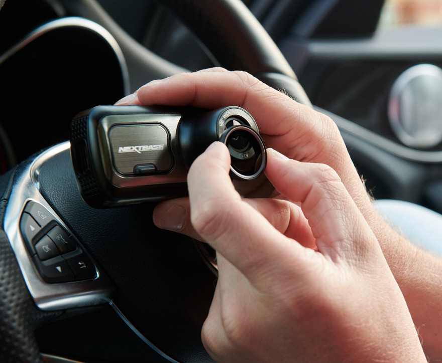 A person holding a camera device inside a car.