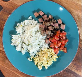 Steak, rice, corn, and pico de gallo served on a blue plate. View this post on Tastefully Simple's Instagram.
