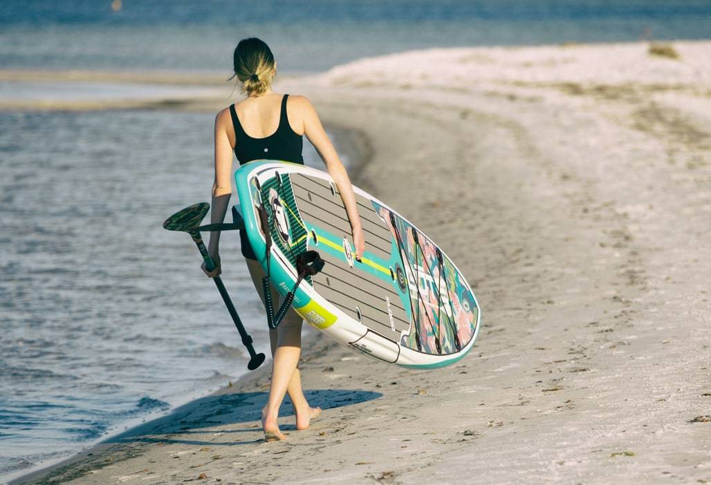 A person carrying a Flood Gatorshell paddle board