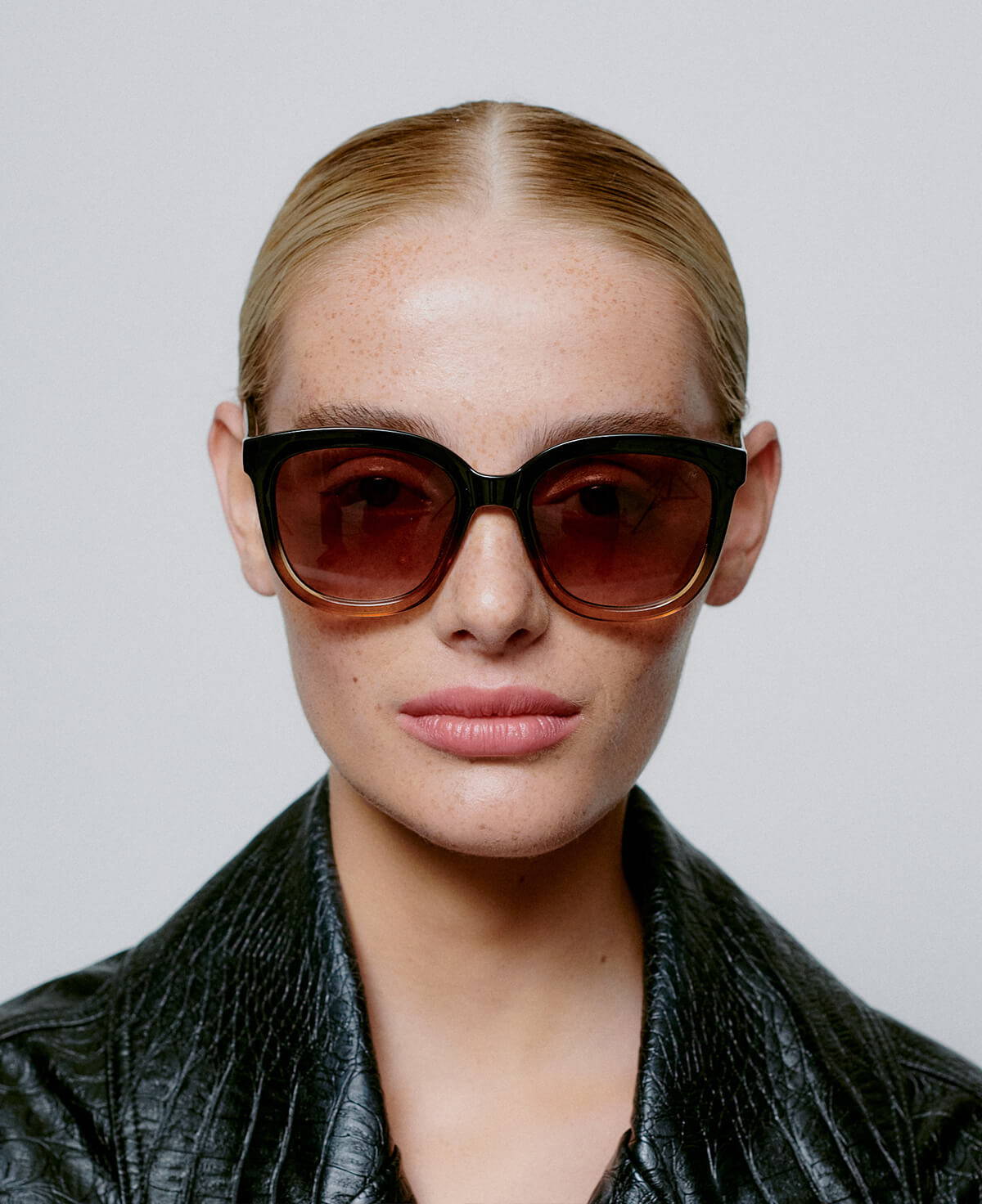 A picture of a model wearing the A.Kjaerbede Billy sunglasses in Black to Brown Transparent.