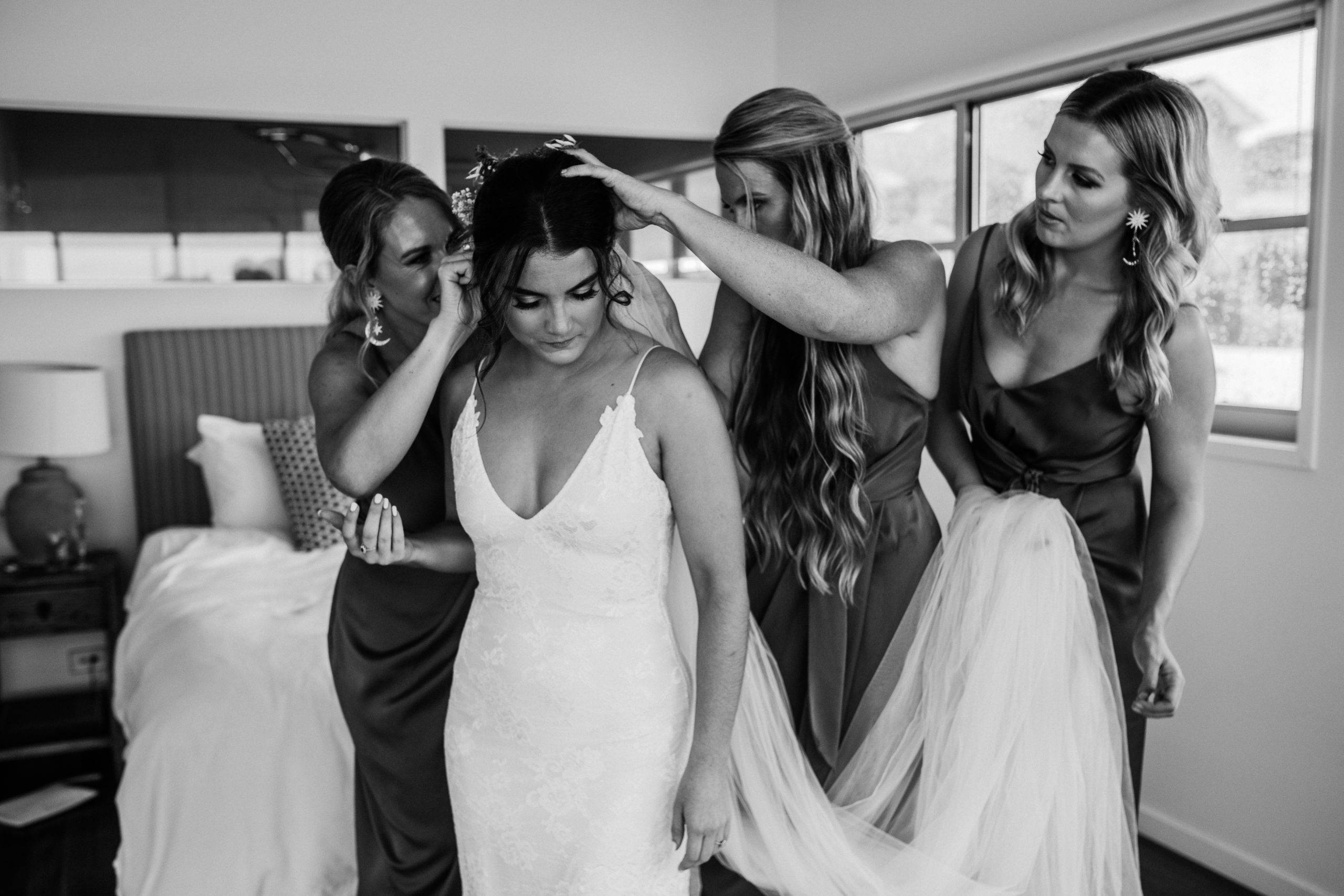 Bridal party fixing the brides hair wearing a white lace dress