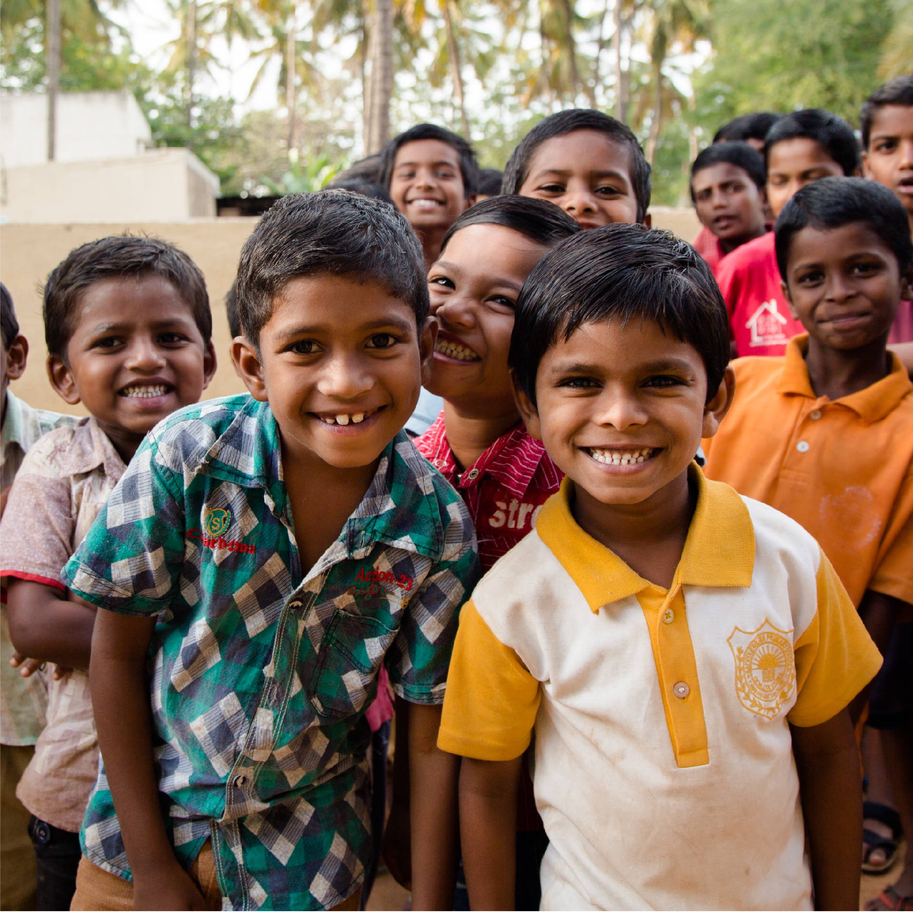 a large group of young Indian boys, around the age of 10, pose smiling and looking tough. 