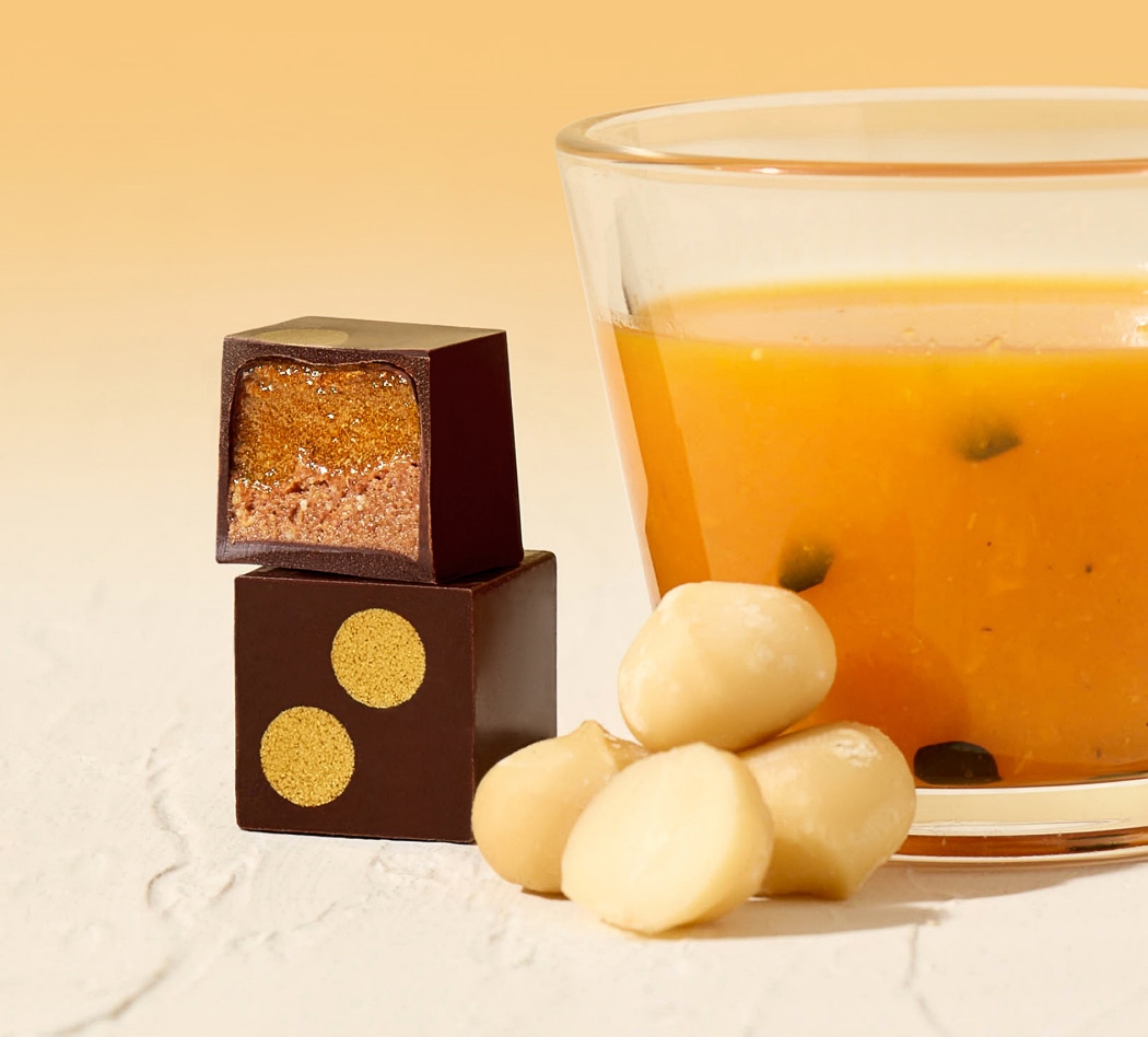 Chocolate pieces and a glass of orange drink on a light background.