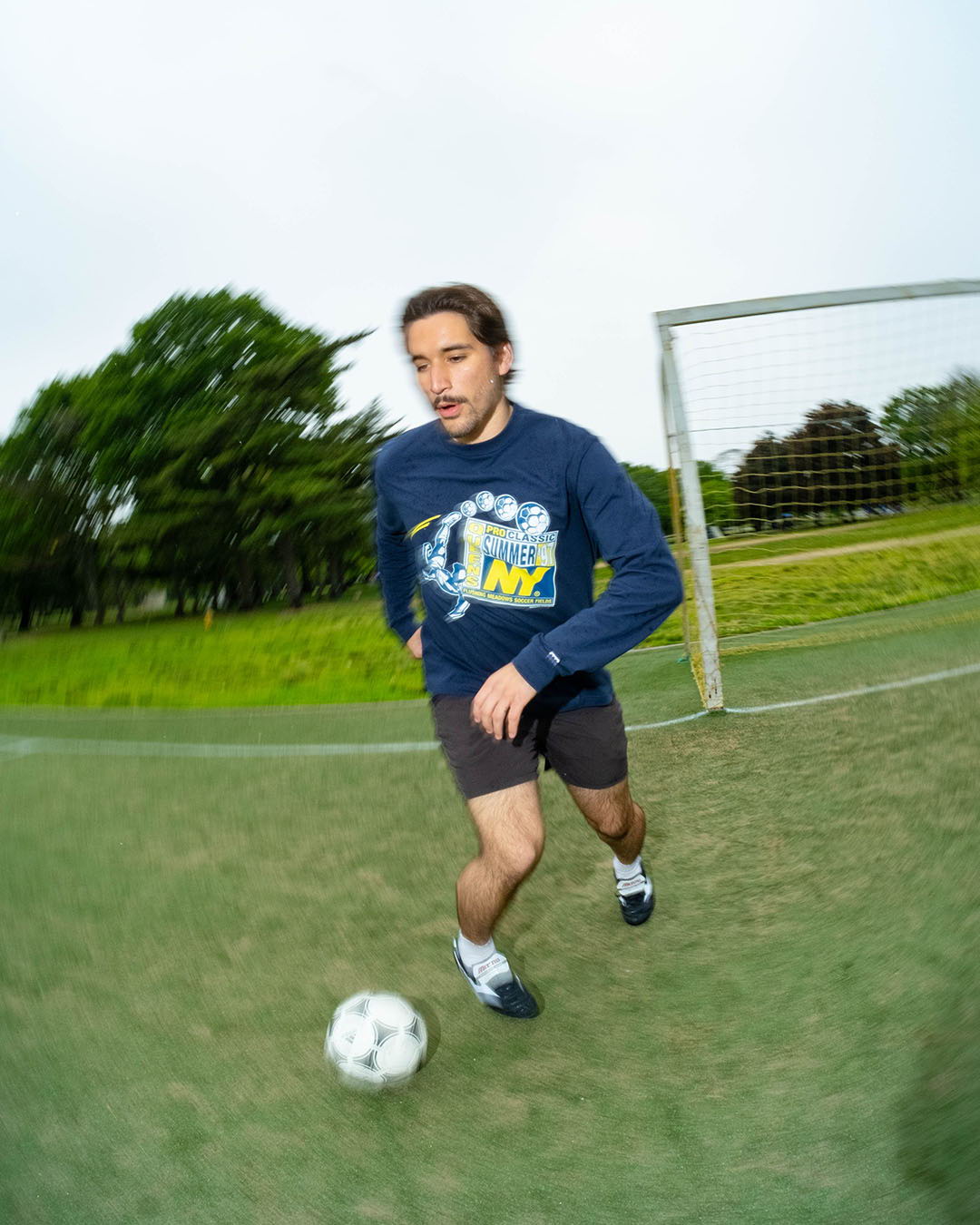A young man running with a soccer ball on a field.
