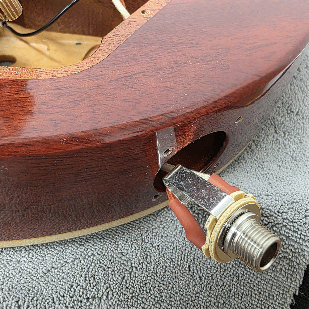 Guitar body with a mounted input jack and internal wiring visible.