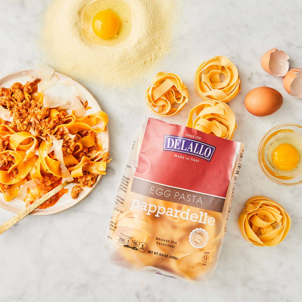 Open bag of DeLallo pappardelle pasta laying on a marble table