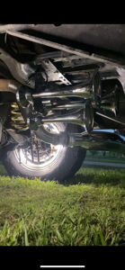 Four chrome train horns mounted under the rear of Malachi's Ford F250 with illuminated wheel at night