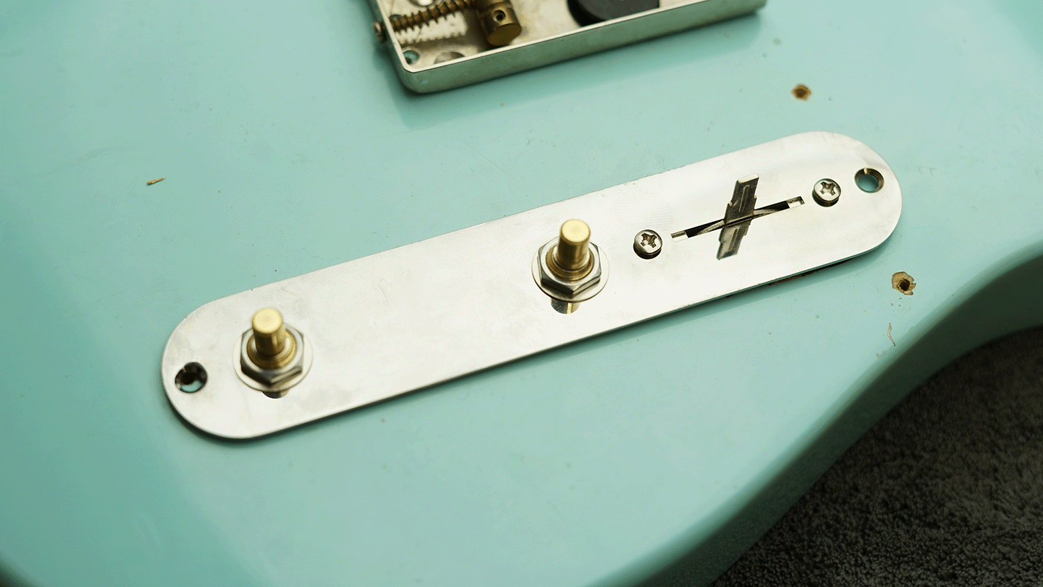Close-up of guitar control plate with knobs and switches.
