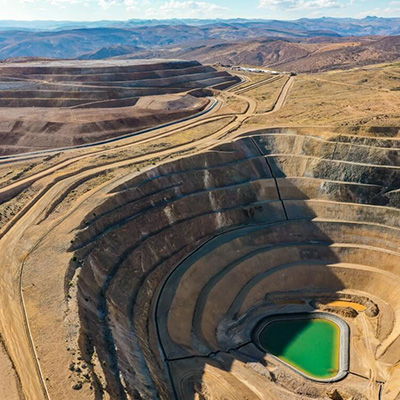 Aerial view of a large quarry with green water and layered terrain.