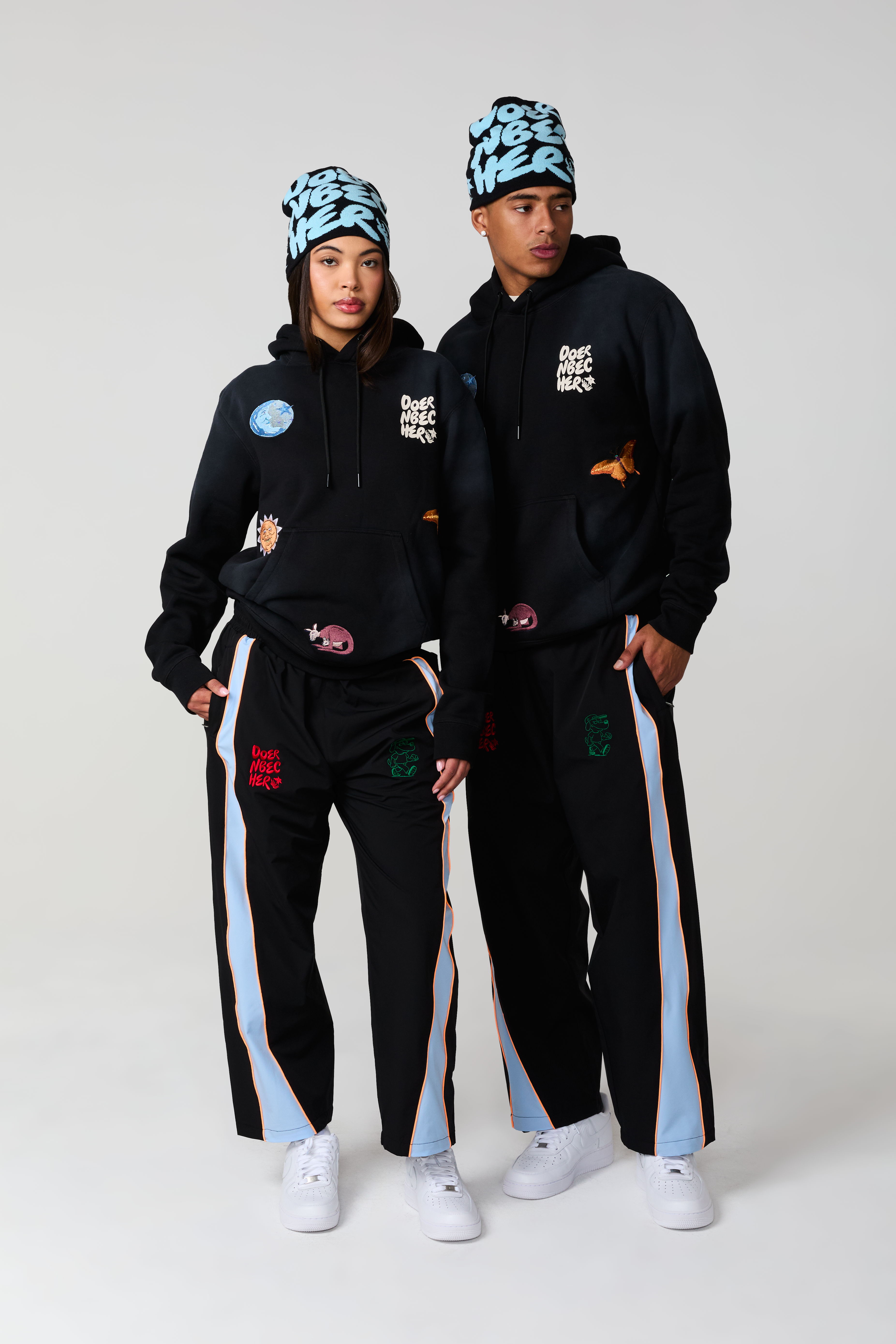 Two models wearing matching streetwear outfits with beanies.