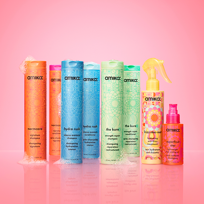 Colorful hair care products displayed against a pink background.