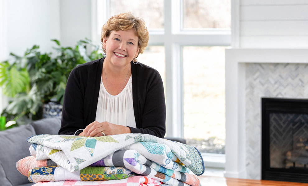 Jenny Doan with a pile of handmade quilts