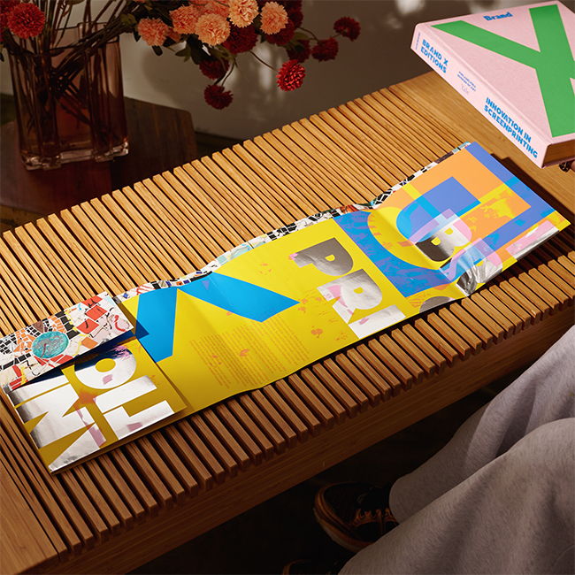 Colorful paper on a wooden table with flowers in the background.