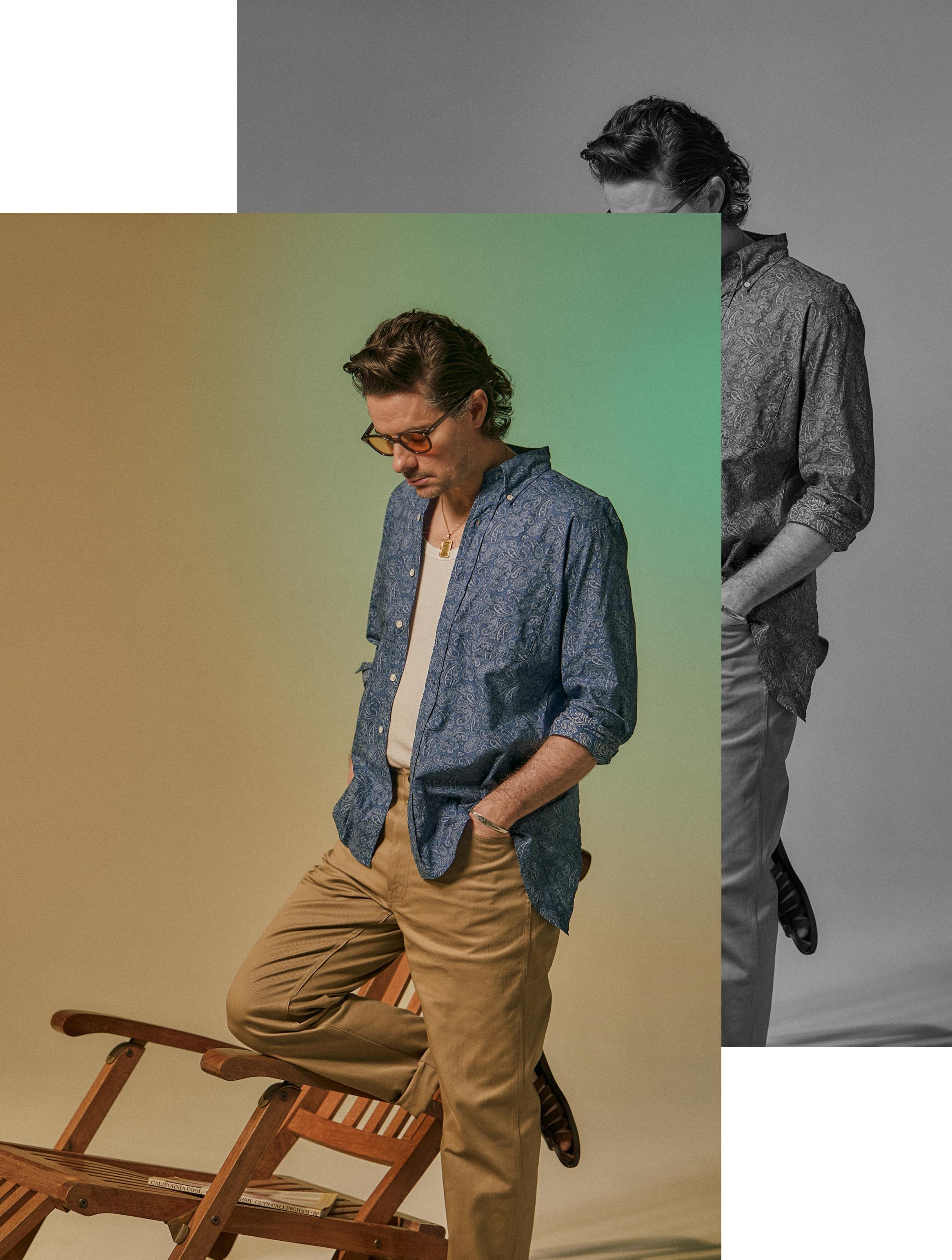 A man in a blue shirt poses beside a wooden chair.
