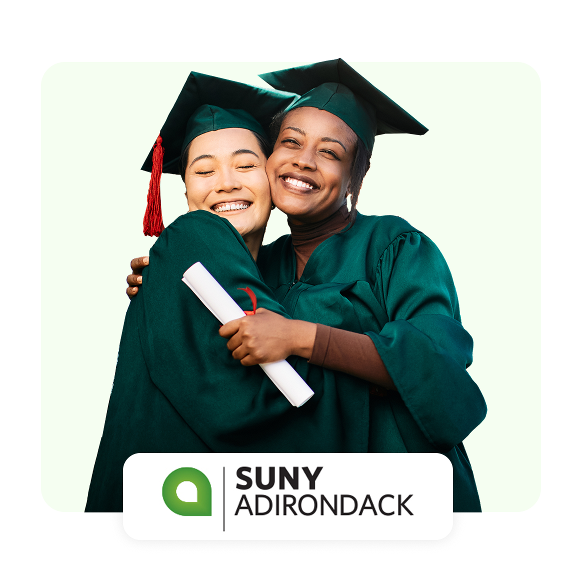 Two graduates in caps and gowns embrace joyfully, celebrating their achievement.