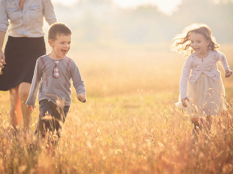 Een jongetje en meisje rennen blij in een veld