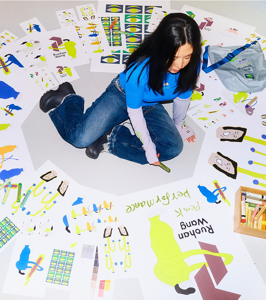 Person sitting on the floor surrounded by colorful artwork and materials.