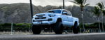 Low-angle front three-quarter white lifted Toyota Tacoma TOYOTA grille halo headlights CRUSE7 Hawaii mountains palms Christian's Conductor's Special 232 featured gallery photo 1