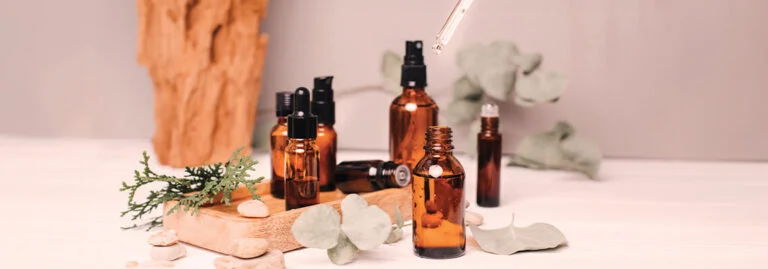 Various amber glass bottles and greenery arranged on a neutral background.