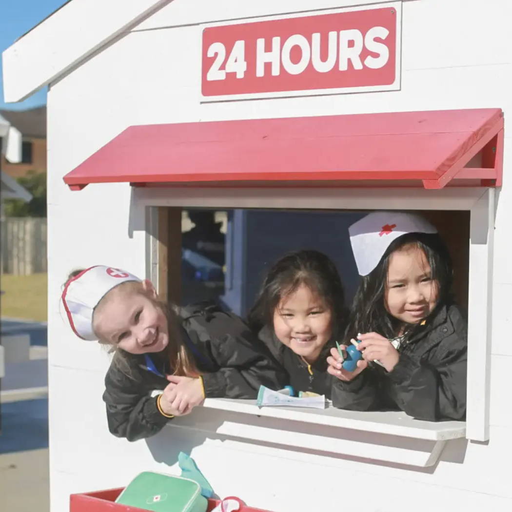 children smiling inside a cubby house