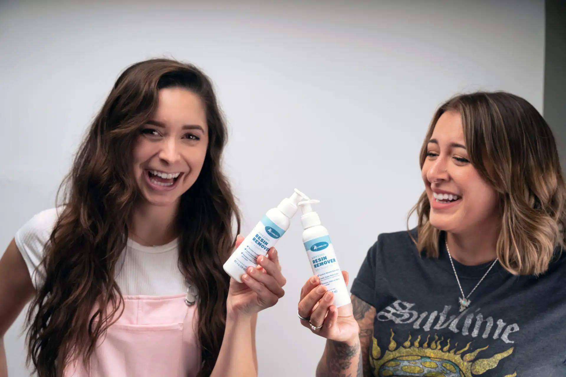 Kelly Johnson and Jessica Abella holding bottles of Alumilite Amazing Resin Remover