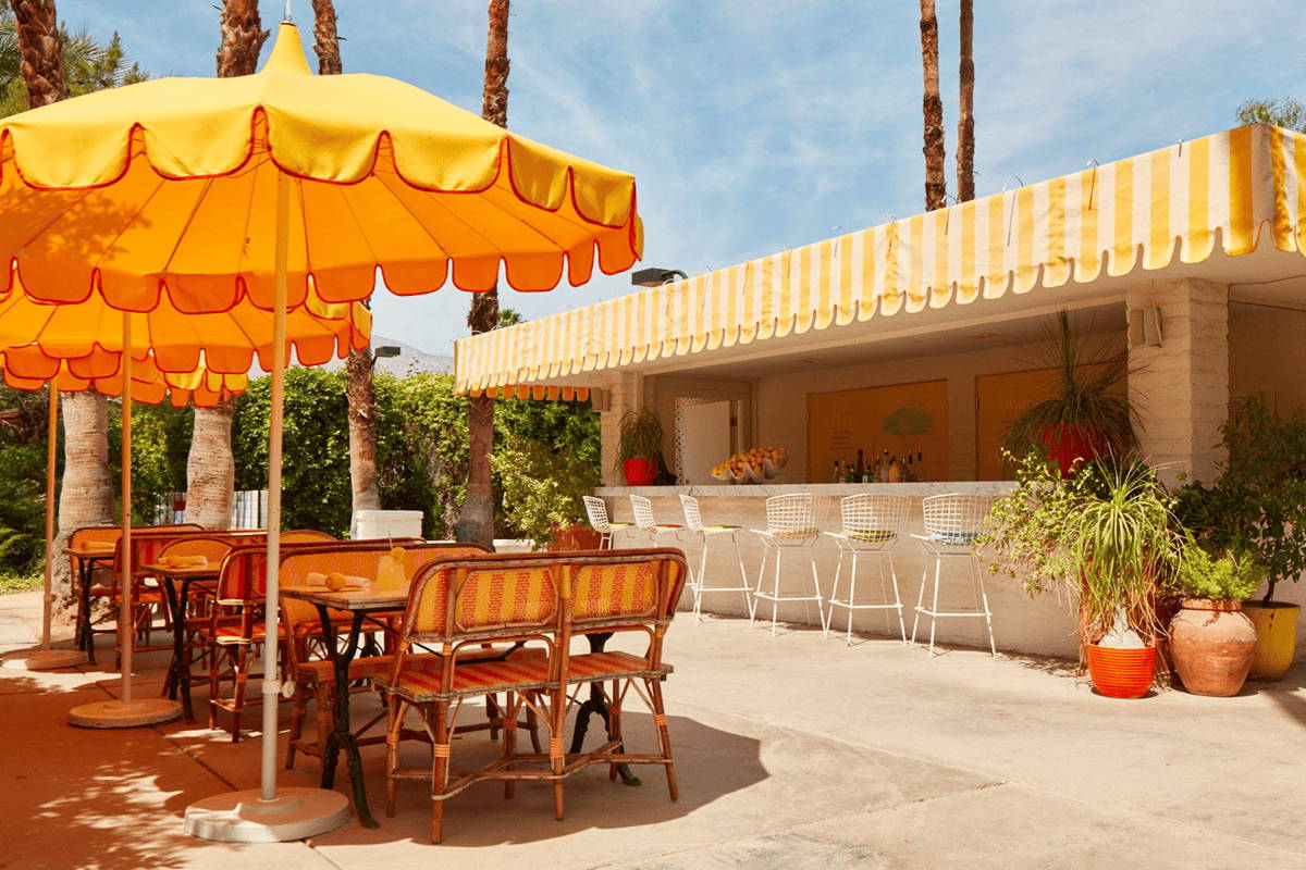 Bright yellow umbrellas create shade for dining tables at a hotel outdoor dining area.