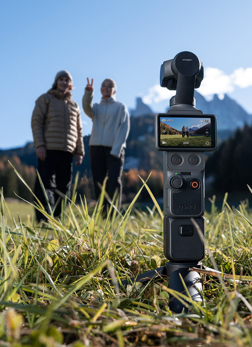 An Osmo Pocket 4 on tripod with two people posing in the background.