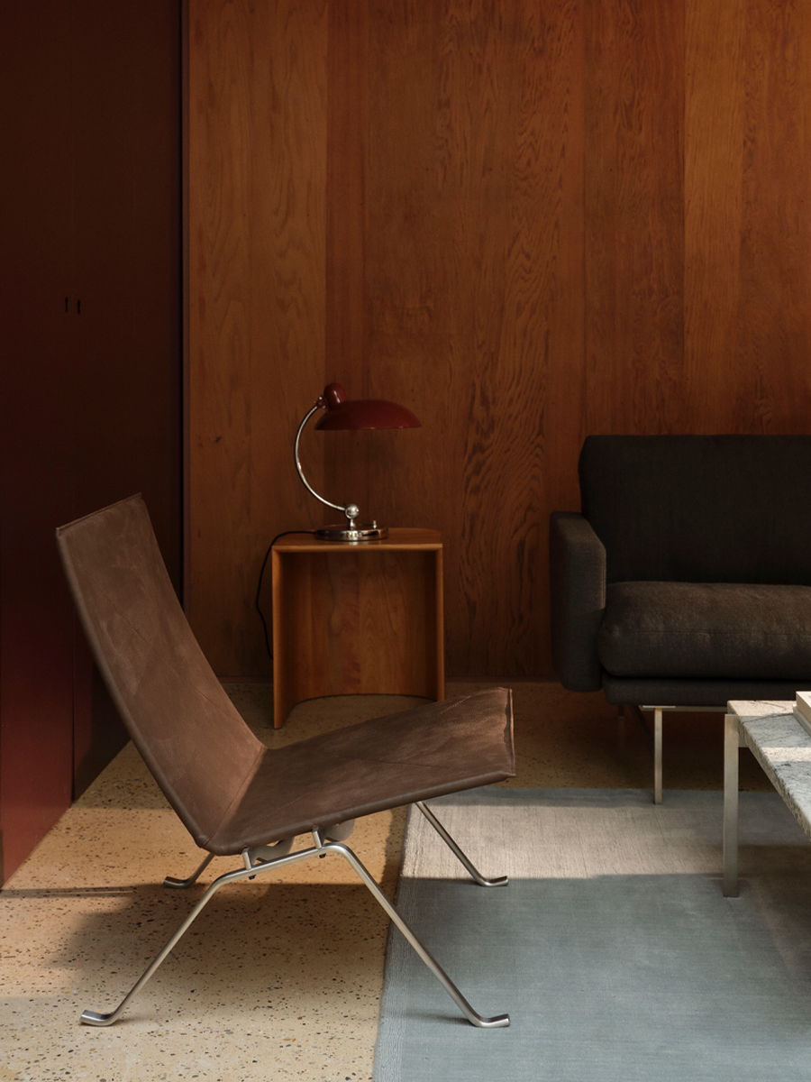 Modern interior with a brown chair, lamp, and dark sofa.