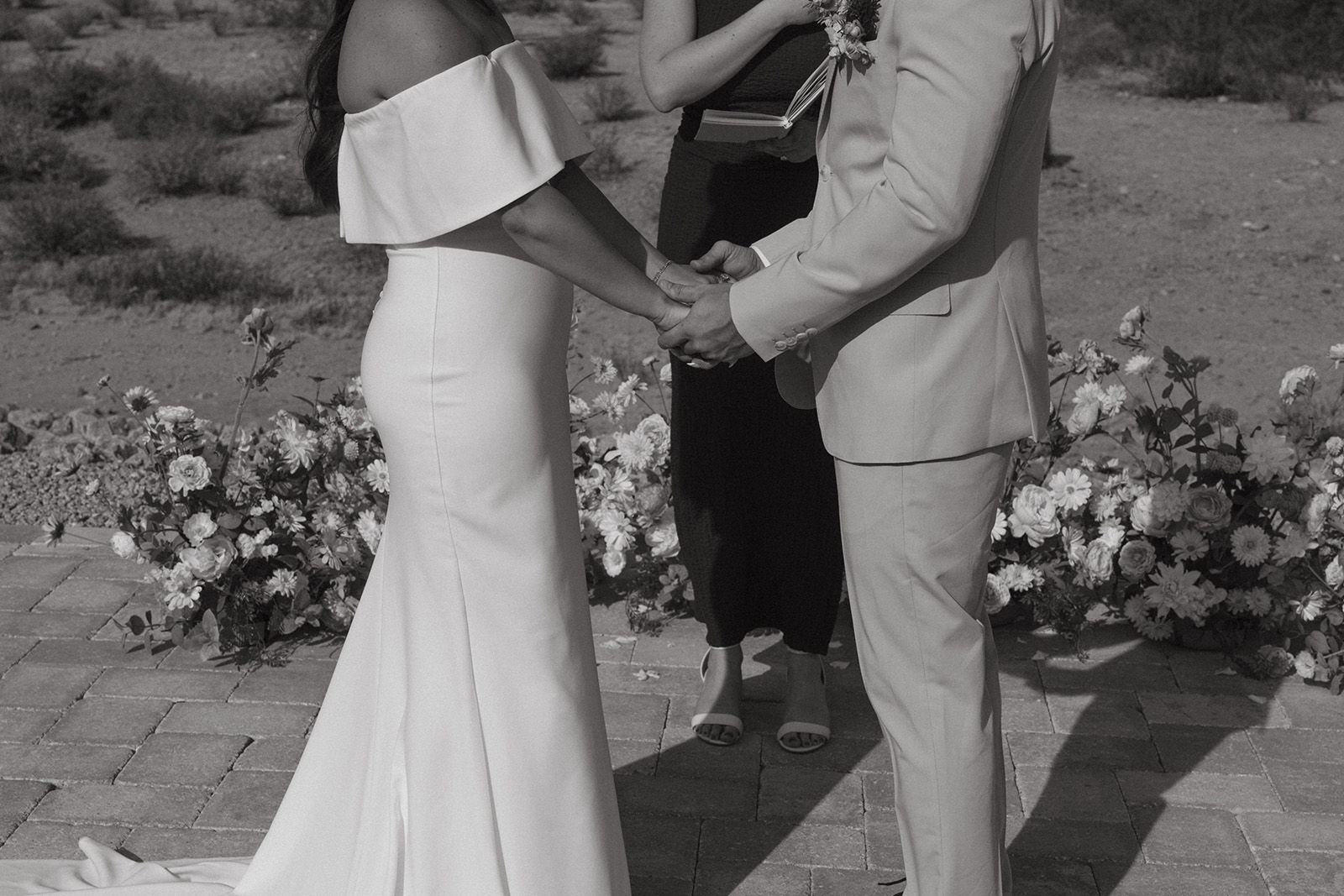 Couple exchanging vows at a wedding ceremony, surrounded by floral arrangements.