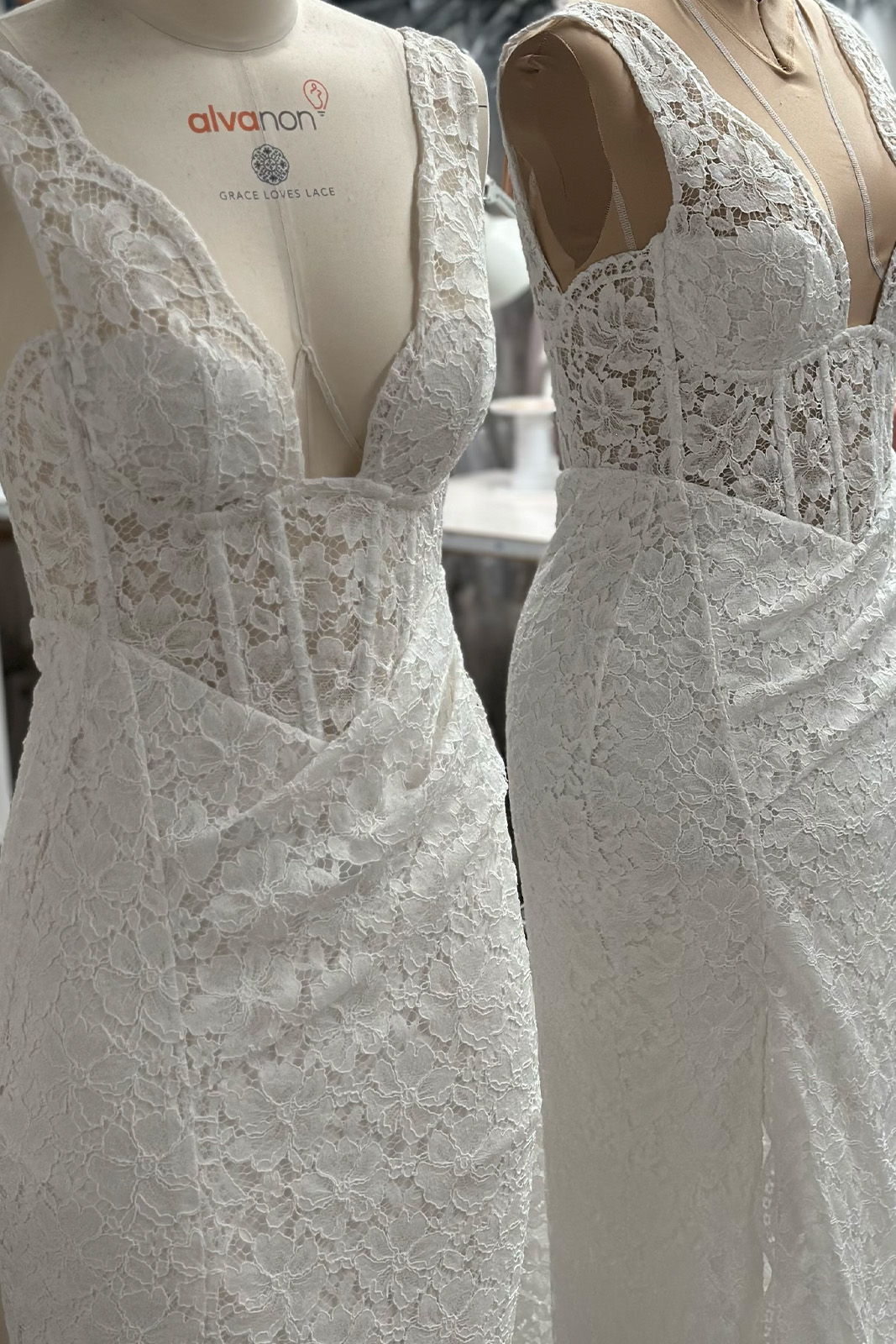 Two elegant white lace dresses displayed on mannequins.