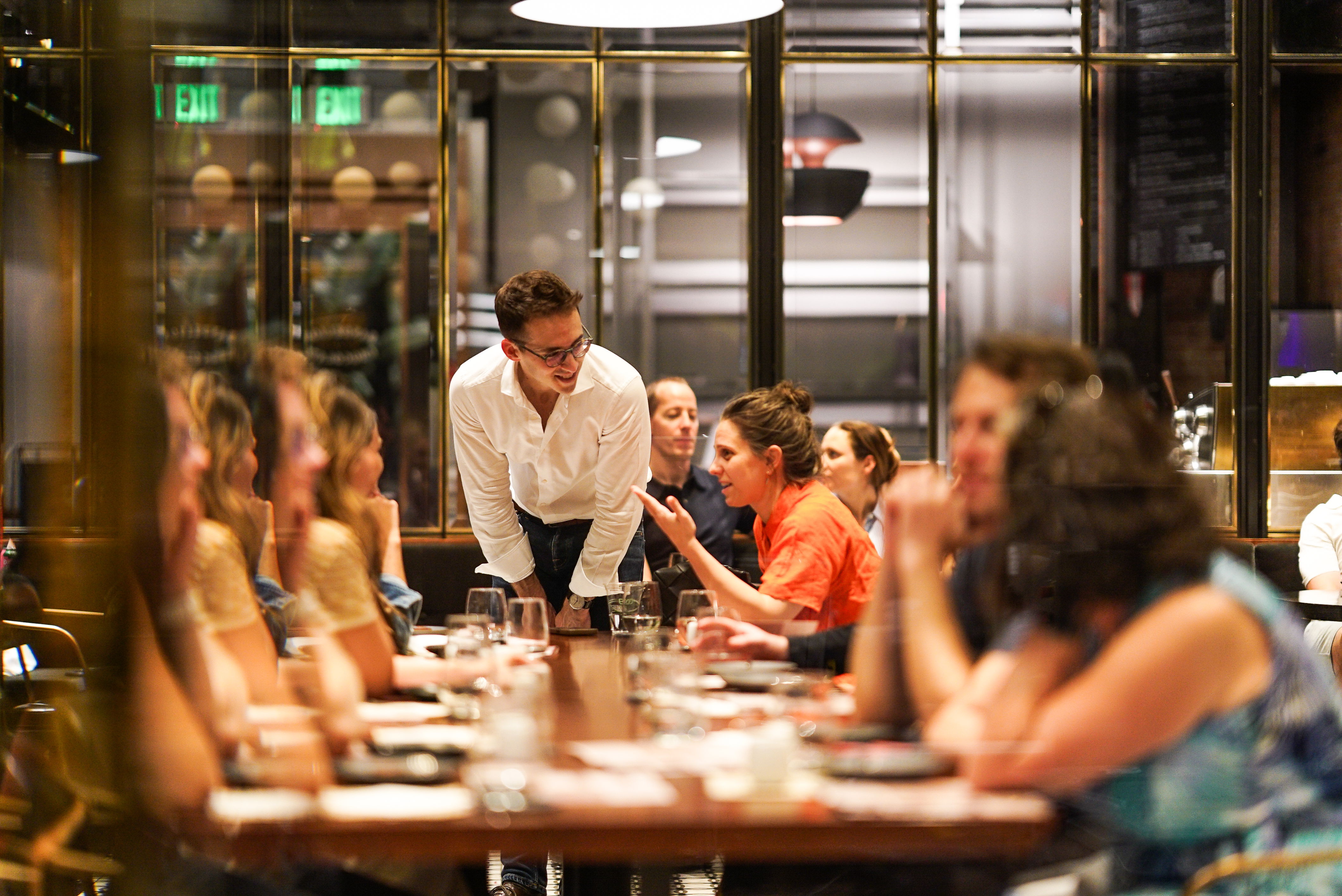 A waiter serves a table of diners in a restaurant setting.
