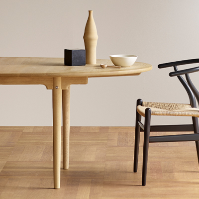 A wooden table with a vase, bowl, and a chair.