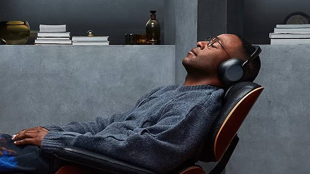 Person wearing headphones, relaxing in a chair, eyes closed.