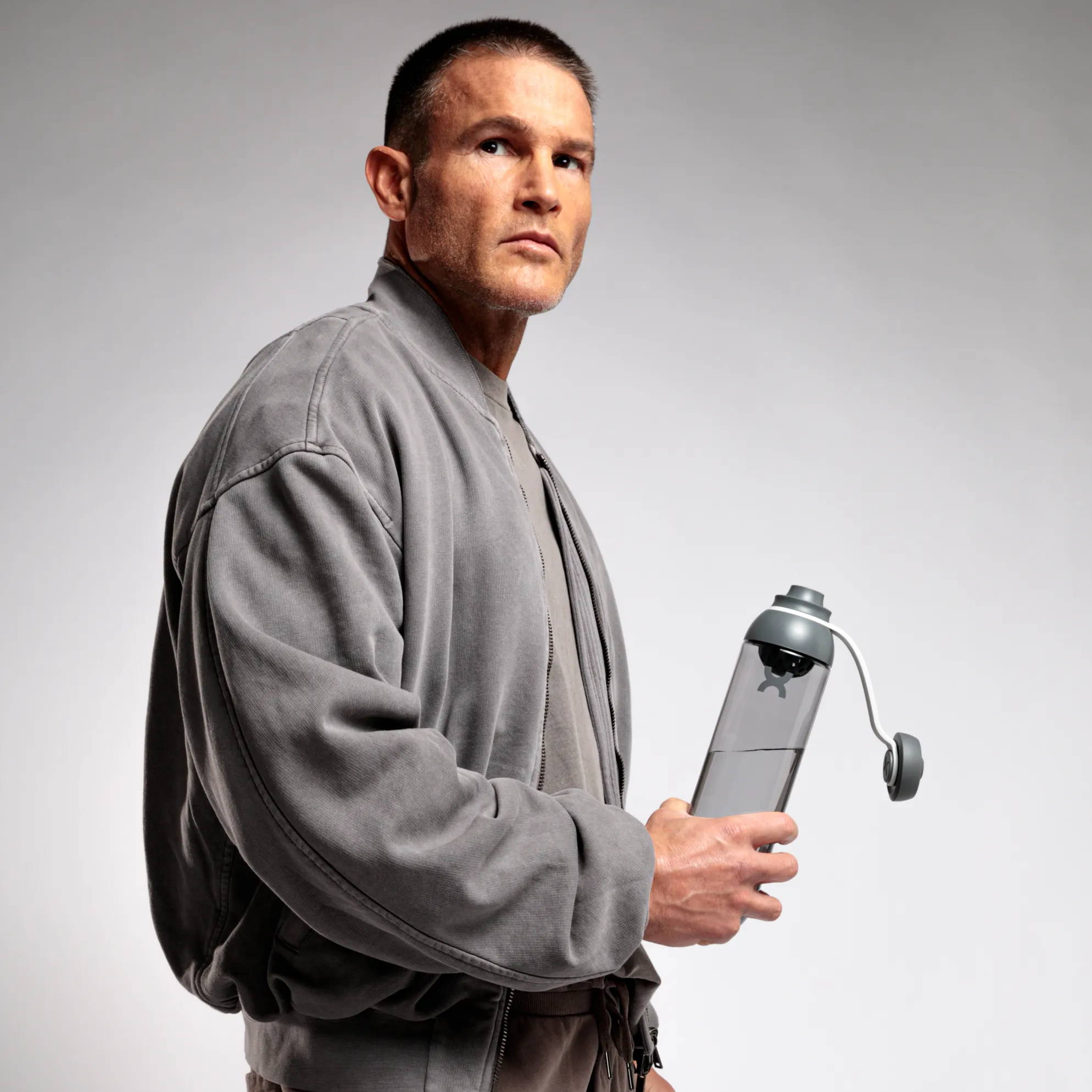 man in gray tracksuit holding FORM, hybrid water bottle 