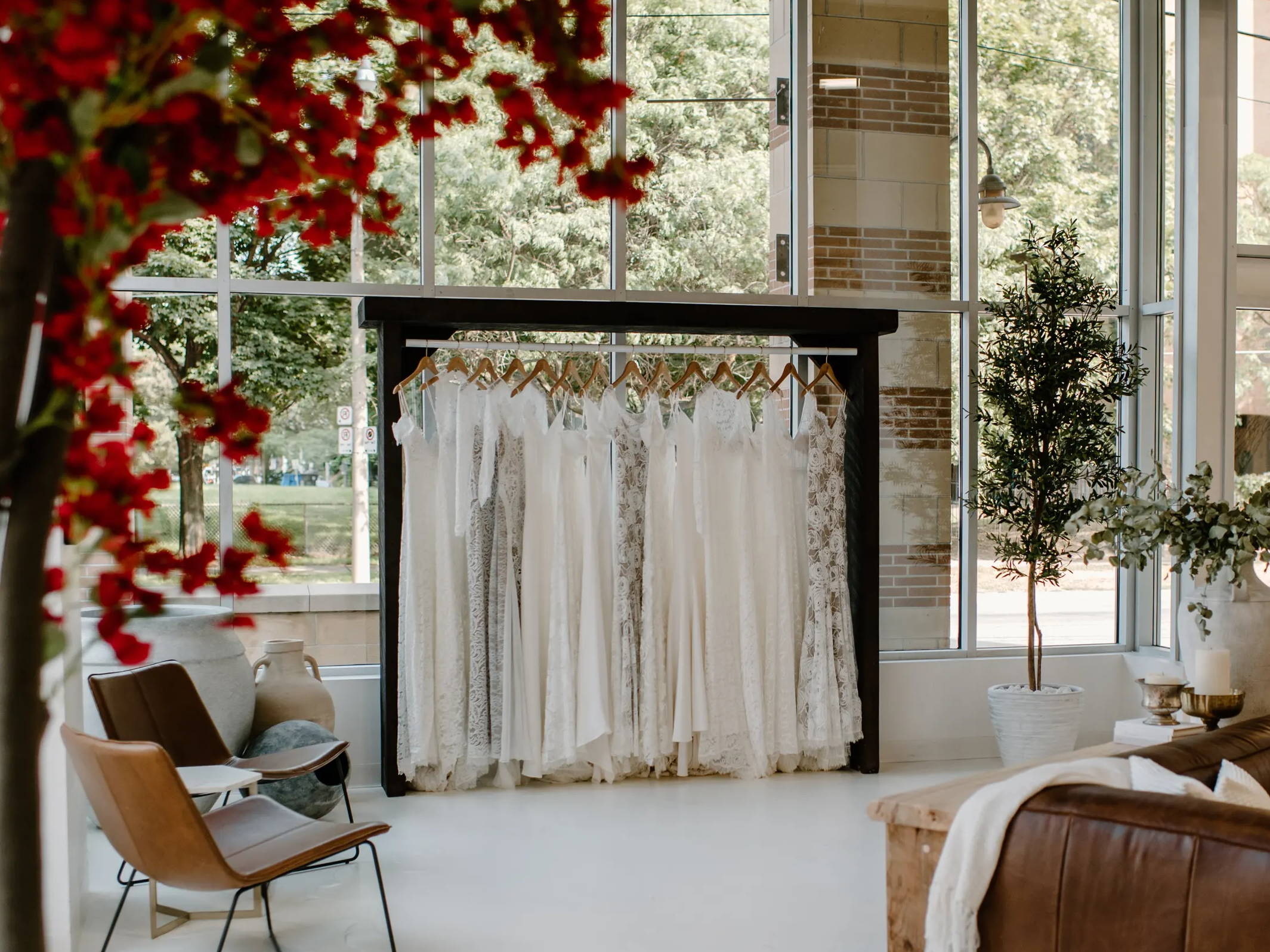 Grace Loves Lace dresses hanging on black rack with red bougainvillea 