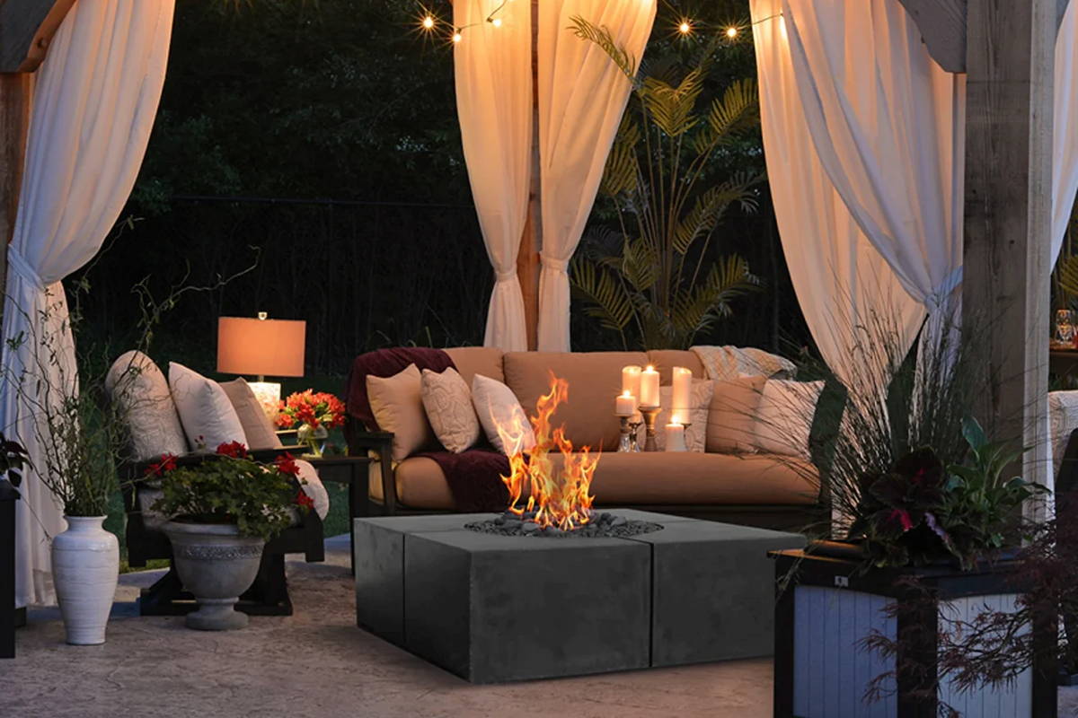 A cozy patio featuring a concrete fire pit and comfortable couches, perfect for outdoor relaxation.