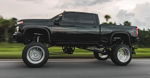 Side rolling view of black lifted Silverado 2500HD thumbnail