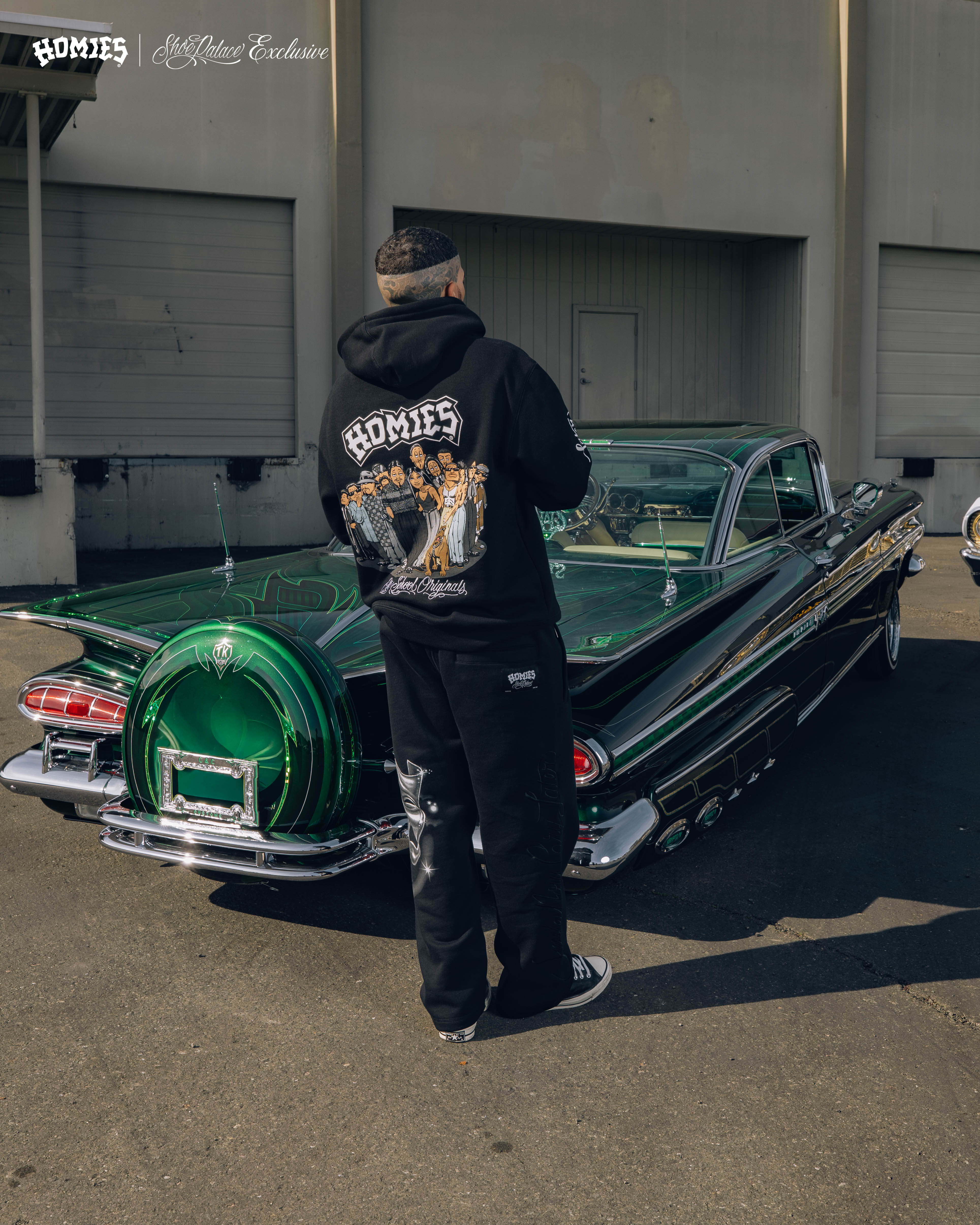 Person in a hoodie standing beside a classic green car.