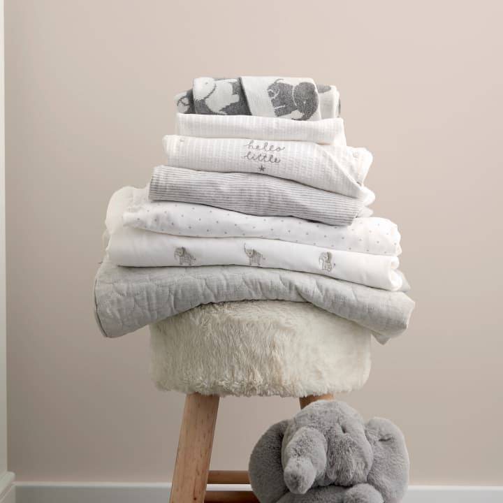Stacked blankets on a stool next to an elephant soft toy