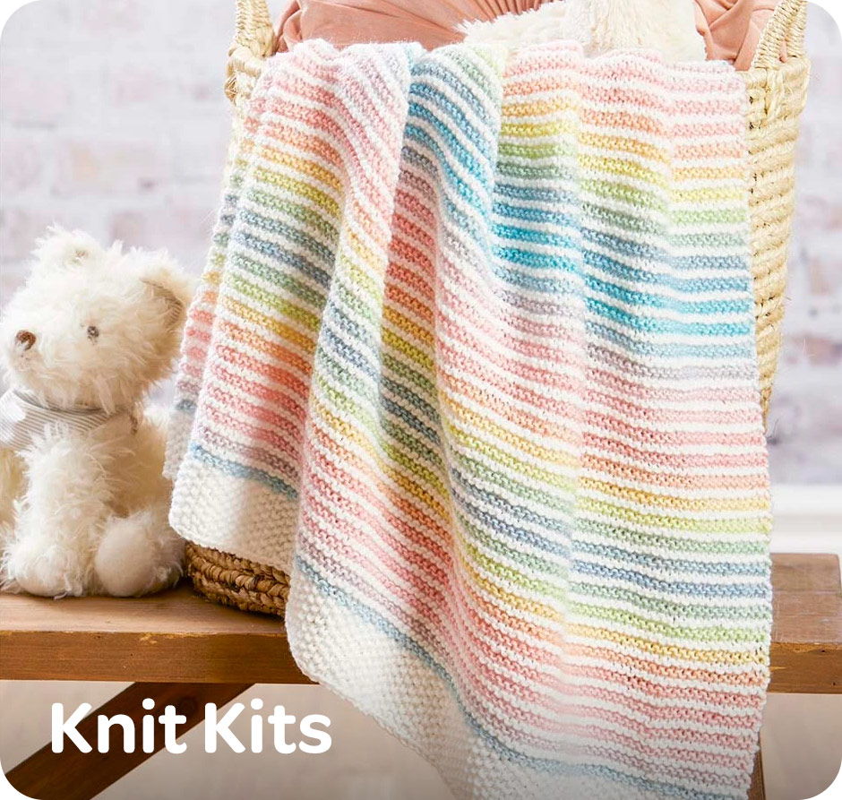 A colorful knitted blanket draped over a basket next to a teddy bear with text 